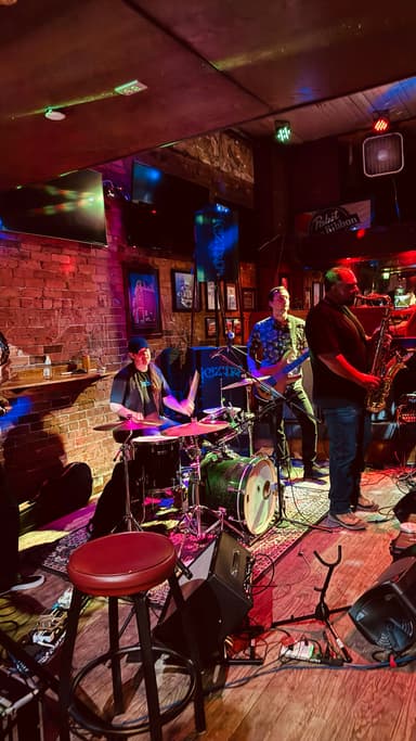 Un groupe de musiciens jouant dans un bar avec des lumières colorées.