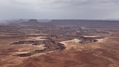 Un paysage désertique avec des formations rocheuses et une rivière sinueuse.