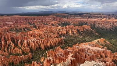 Un paysage de formations rocheuses rouges sous un ciel nuageux.