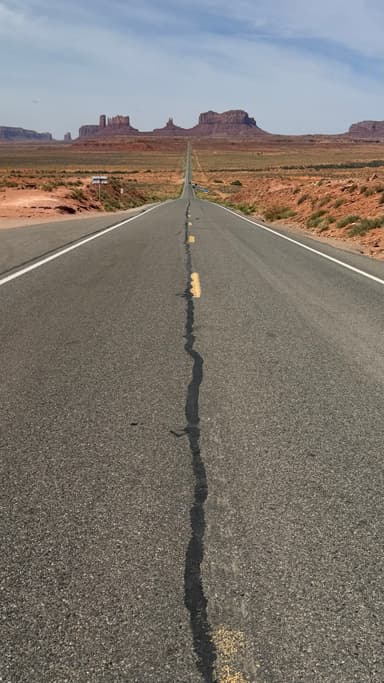 Une route menant à des formations rocheuses sous un ciel bleu.