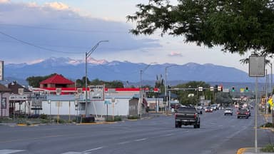 Une rue avec des montagnes en arrière-plan et des voitures.