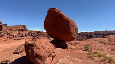 Un rocher en équilibre sur un autre dans un paysage désertique.