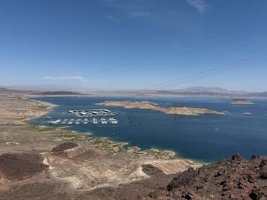 Vue panoramique d'un lac avec des bateaux et des collines environnantes.