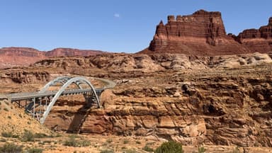 Un pont moderne sur un paysage désertique avec des formations rocheuses rouges.