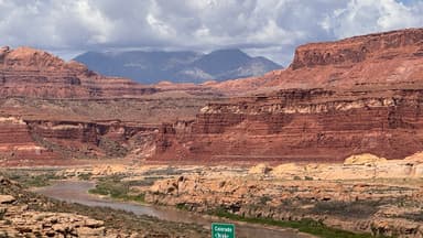 Un paysage de canyons et montagnes sous un ciel nuageux.