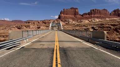Un pont traversant un paysage désertique avec des formations rocheuses rouges.