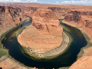 Un paysage de canyons et une rivière sinueuse sous un ciel bleu.