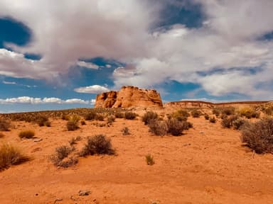 Un paysage désertique avec des formations rocheuses et un ciel nuageux.