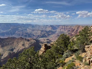 A panoramic view of a canyon with rocky cliffs and green vegetation under a blue sky.