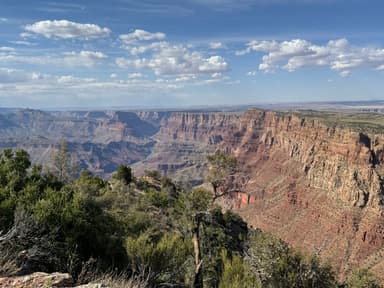 A panoramic view of a canyon with layered rock formations and a blue sky.