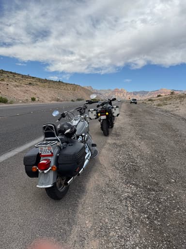 Deux motos garées sur le bord de la route avec des montagnes en arrière-plan.