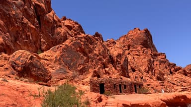 Des rochers rouges et une structure en pierre sous un ciel bleu.