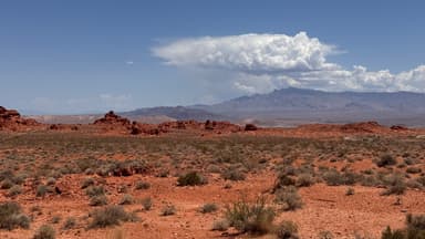 Un paysage désertique avec des montagnes au loin sous un ciel bleu.