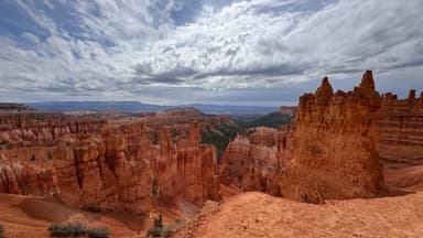 Un paysage de formations rocheuses rouges sous un ciel nuageux.