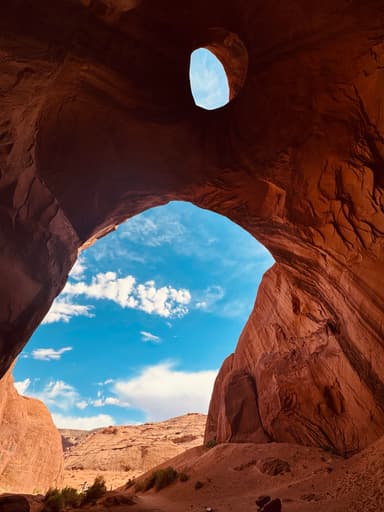 A view of a rock formation with a hole and blue sky in Arizona.
