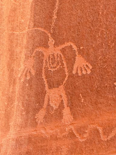 A petroglyph of a figure on red rock in Arizona.