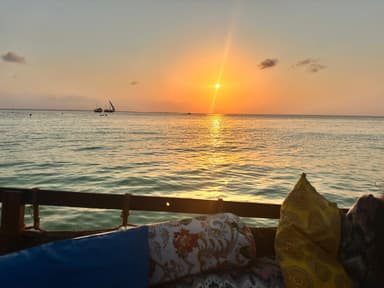 A sunset over the ocean with boats in the distance.