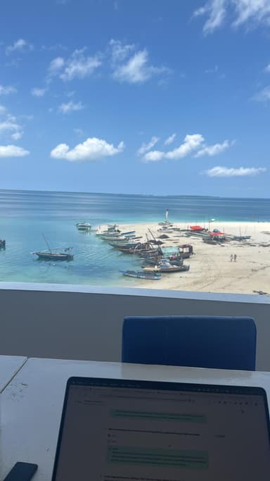 A serene beach scene with boats and clear blue water under a bright sky.