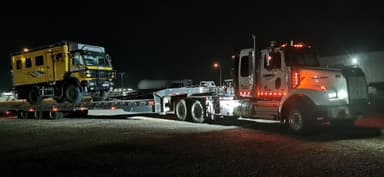 Un camion de transport avec un véhicule tout-terrain à la nuit.