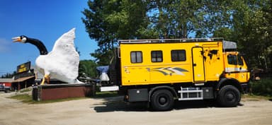 Un camion jaune à côté d'une grande statue de cygne.