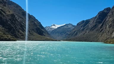 Un paysage de montagnes et un lac turquoise sous un ciel bleu.