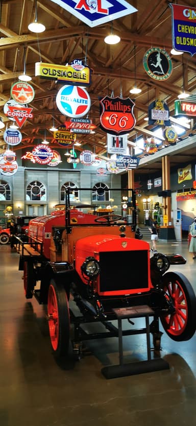 Un ancien camion rouge dans un musée avec des enseignes lumineuses au plafond.
