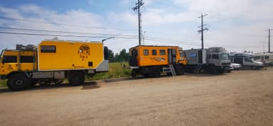 Des camions de voyage colorés garés sur un chemin de terre.