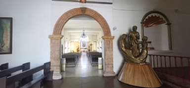 Une vue intérieure d'une église avec une sculpture dorée et des bancs en bois.