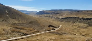 Un paysage montagneux aride avec une route sinueuse.