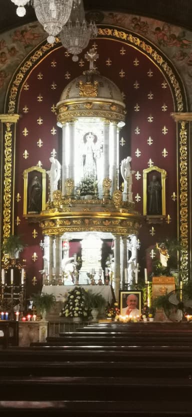 Une église avec un autel richement décoré et des bougies allumées.