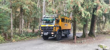 Un camion jaune circulant dans une forêt canadienne.