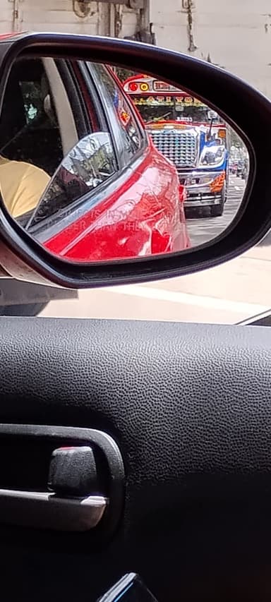 Une vue de la route avec des véhicules dans un rétroviseur.