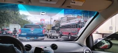 Une scène de circulation à San Lucas Sacatepéquez, avec des voitures et un bus coloré.