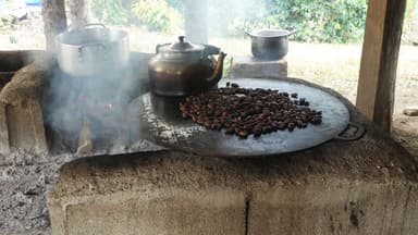Des grains de café torréfiés sur une plaque en métal avec une bouilloire à côté.