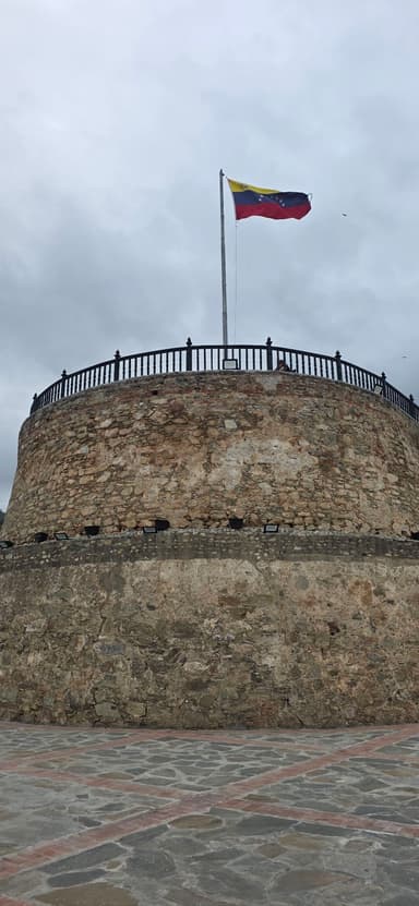Un fort en pierre avec un drapeau au vent sous un ciel nuageux.