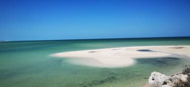Une plage tranquille avec des eaux turquoise et un ciel bleu.