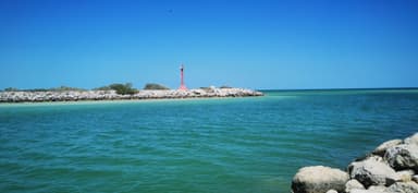 Un phare rouge sur une île au large de la côte turquoise.