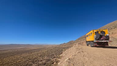 Un véhicule sur une route de montagne avec un ciel bleu clair.