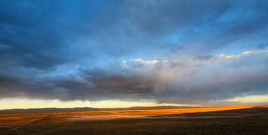 Un paysage vaste avec des nuages et une lumière dorée au coucher du soleil.