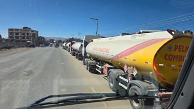 Des camions-citernes alignés sur une route ensoleillée.
