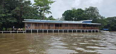 Un bâtiment en bois au bord d'une rivière, entouré de verdure.