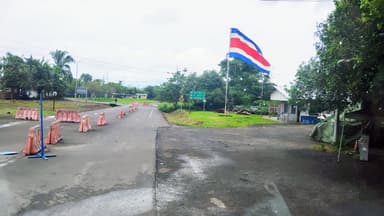 Une route avec des barrières et un grand drapeau costaricien.