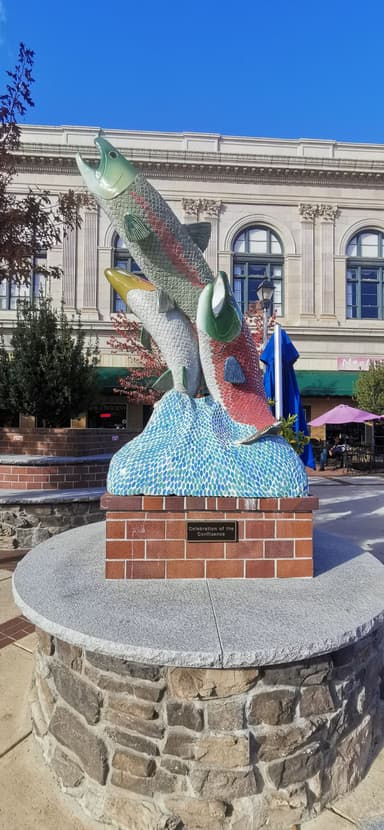 Une sculpture colorée de poissons sur un socle en briques.