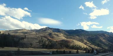Des collines sèches sous un ciel bleu avec des nuages.