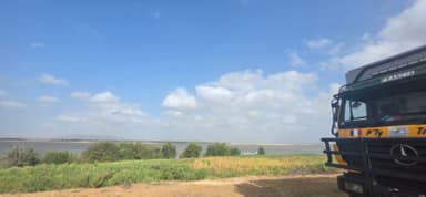 Un camion près d'un paysage fluvial sous un ciel nuageux.