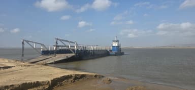 Un ferry amarré sur une rivière sous un ciel bleu.