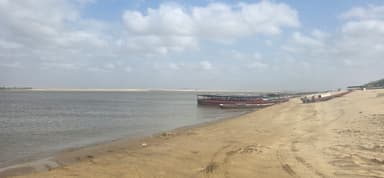 Une vue de la plage avec des bateaux sur l'eau et des nuages dans le ciel.