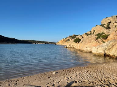 Une plage avec des rochers et un ciel bleu à Sardinia.