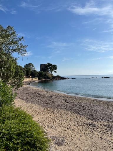 Une plage tranquille avec une tour au loin sous un ciel bleu.