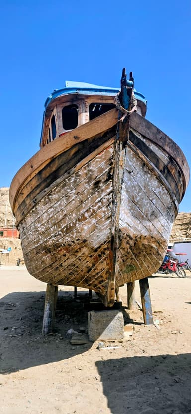Un bateau en bois sur la plage sous un ciel bleu.